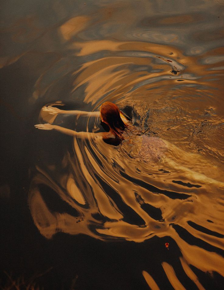 A woman resting in golden water at last light